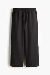 Pantalón jogger de algodón con corte relajado, cintura elástica con cordón ajustable, piernas rectas y bolsillos de parche delanteros.