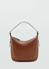 Bolso de hombro color marrón con diseño estructurado, cierre de cremallera superior y detalle de tachuelas metálicas doradas en el contorno frontal. Cuenta con un asa ajustable con hebilla.