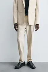 Pantalón de corte recto confeccionado en tejido con lana, color beige. Presenta bolsillos frontales, bolsillos traseros de vivo y cierre frontal con cremallera y botón.