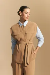 Camisa de corte clásico y holgado, confeccionada en tela blanca, con cuello camisero, cierre frontal de botones de nácar y mangas largas con puños abotonados.