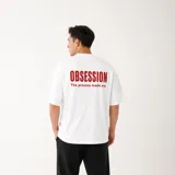 Remera oversize blanca de algodón pesado, con diseño unisex, cuello redondo, mangas cortas y estampa gráfica en rojo en la espalda con la leyenda "OBSESSION - The process made me.".