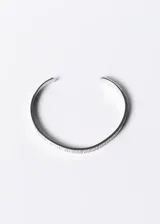 Pulsera esclava abierta de acero quirúrgico color plateado, con diseño de guarda griega.