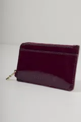 Tarjetero de cuero con estampado animal print blanco y negro. Incluye ranuras para tarjetas en el frente y cierre metálico superior con tirador con el logo de la marca.