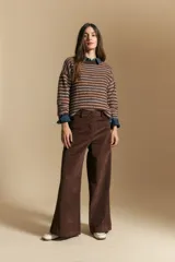Pantalón de pana de tiro alto con corte wide leg, diseño de pierna amplia y cierre frontal con botones visibles. Presenta bolsillos laterales y una textura acanalada característica del tejido.