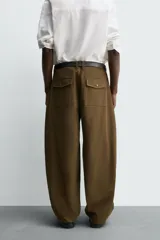 Pantalón de corte balloon fit, color negro, con bolsillos laterales de vivo y bolsillos traseros con solapa. Presenta cierre frontal con cremallera y botón.