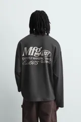 Camiseta de manga larga y cuello redondo con corte relajado, color gris oscuro, con estampado de texto en contraste en el pecho.