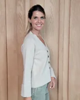 Cardigan de punto color beige, con escote en V, cierre frontal de botones y mangas largas con puños anchos acanalados.