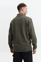 Buzo de tejido de punto color verde oliva, con cuello alto y cierre frontal parcial. Presenta un pequeño logo bordado en el pecho.