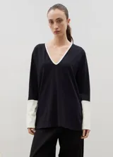 Remera de algodón con escote en V, manga larga y diseño bicolor. Presenta cuerpo en color beige con detalles en negro en el escote, los puños y los tajos laterales.