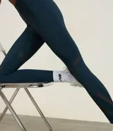Legging deportiva de tiro alto en color azul oscuro, confeccionada en microfibra de poliamida y elastano. Presenta recortes laterales en tela de malla para mayor transpirabilidad y un ajuste ceñido al cuerpo, ideal para actividades de alta intensidad.