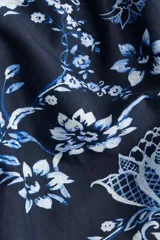 Vestido midi de algodón azul marino con estampado floral y geométrico en tonos celestes y blancos. Presenta escote recto, breteles ajustables con moñas, cuerpo entallado y falda acampanada con volados fruncidos en la parte inferior.