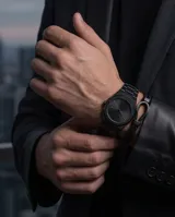 Pulsera tipo esclava compuesta por una doble tira de cuero trenzado negro y un cierre central de acero en forma de herradura.