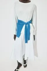 Jersey de punto liso, color azul brillante, con cuello redondo y manga larga. Presenta acabados en rib en puños, cuello y bajo, con aberturas laterales en el ruedo.