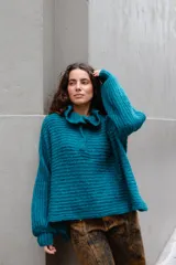 Buzo de tejido de punto en mezcla de lana y alpaca, color gris. Presenta una silueta amplia con cuello tipo polo que incluye broches para convertirlo en polera, mangas largas con puños y un diseño de tejido horizontal.