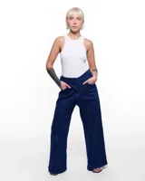 Pantalón de denim azul con corte sastrero de pierna ancha, tiro alto, cierre frontal invisible y pretina cruzada. Aplique de caballo/dragón en bronce hecho a mano y bordado negro del logo Temblad en la parte trasera.