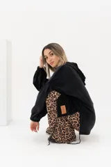 Buzo canguro negro de tejido suave, con capucha y bolsillo canguro frontal. Presenta puños y cintura elásticos.