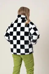 Campera de poliéster símil piel, con estampado a cuadros blancos y negros, cierre frontal y bolsillos laterales.