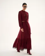 Camisa de manga larga color bordó, con cuello mao, cierre frontal con botones ocultos y detalle de encaje en el frente y las mangas. Presenta un diseño con lazo frontal para anudar en la cintura.