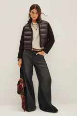 Campera híbrida con frente acolchado tipo puffer en color negro y mangas de tejido liso al tono. Presenta cuello alto, cierre frontal y diseño entallado.