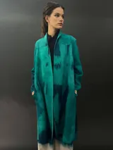 Tapado largo gris de lana merino con bolsillos laterales y corte particular en los hombros.