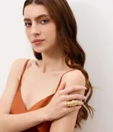 Anillo maxi de metal dorado con diseño orgánico y volúmenes superpuestos en relieve.