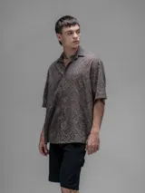 Camisa clásica de manga corta, color chocolate con efecto desgaste, confeccionada en algodón bordado (broderie) con diseño floral calado. Presenta cuello abierto y calce oversize.