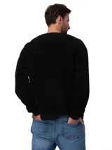 Buzo de cuello redondo confeccionado en tejido sherpa negro, con textura suave y elástica. Presenta puños y banda inferior en tejido acanalado y una pequeña etiqueta con el logo de la marca en el pecho.