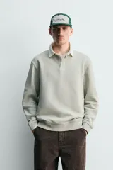 Sudadera de manga larga estilo polo con diseño de rayas horizontales anchas en azul marino y blanco. Presenta cuello de solapa en contraste, cierre frontal con botones ocultos y acabados en rib en puños y bajo.