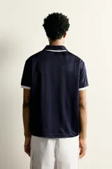 Polo de corte relajado confeccionado en tejido técnico, con diseño de rayas verticales en tonos azul marino y negro. Presenta cuello solapa con abertura frontal y detalles de rib en contraste en cuello y mangas. Incluye estampado frontal con el número 98 y la inscripción France, además de una etiqueta aplicada en el ruedo inferior.