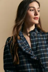 Camisa de algodón a cuadros con diseño de volados frontales, cuello alto y mangas largas con leve volumen.