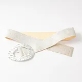 Cinto elástico de color plateado con acabado brillante y hebilla ovalada de metal texturizado.