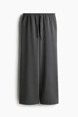 Pantalón de corte holgado en color gris, confeccionado en sarga. Presenta cintura elástica revestida con cordón ajustable, bolsillos laterales discretos y piernas rectas.