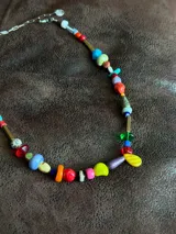 Collar largo confeccionado con cuentas multicolor de diversos materiales, formas y tamaños, incluyendo cristales checos, piedras naturales, acrílico y cerámica. Cuenta con cierre de cadena de acero quirúrgico y ganchito regulable.