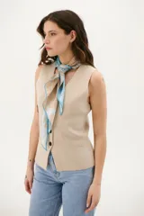 Chaleco tejido de punto en color beige, con escote en V, cierre frontal con botones oscuros y bolsillos frontales decorativos.