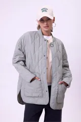 Campera acolchada color gris claro, con cuello mao y cierre frontal con botones a presión. Tiene bolsillos laterales y corte holgado.