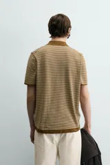 Polo de punto de algodón con corte regular fit, manga corta y cuello solapa con abertura frontal en forma de V. Presenta un diseño a rayas horizontales marrones y beige, con ribetes en color marrón oscuro en el cuello, puños y bajo.
