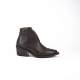 Botín de cuero vacuno color marrón oscuro, con taco de madera foliado en cuero de 5cm de altura, cierre lateral interno y horma de punta fina.
