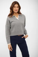Suéter de tejido de punto color gris, con cuello polo y escote en V ribeteado en color beige. Mangas largas con trenzas en relieve y puños ribeteados en color beige.
