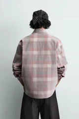 Camisa de corte relajado confeccionada en pana de algodón con diseño de cuadros. Presenta cuello solapa, cierre frontal de botones y mangas largas con puños abotonados.