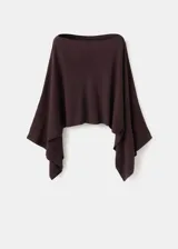 Poncho de punto asimétrico en color bordó, con diseño de capa y cuello barco de mangas amplias.