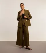 Pantalón de vestir color verde oliva, tiro alto, corte wide leg y pliegues frontales. Incluye trabillas en la cintura y cinturón de cuero sintético negro con hebilla cuadrada.