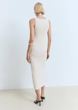 Vestido midi de punto fino color beige, sin mangas, con cuello barco y diseño recto. Incluye un cinturón decorativo tejido a la altura de la cintura.