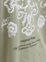 Remera de manga corta color verde militar, de corte oversize y cuello redondo, con pequeño texto estampado en el pecho.