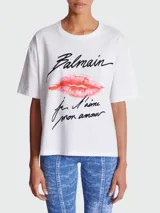 Remera blanca de algodón con estampado de la marca Balmain, con el logo y un beso rojo.