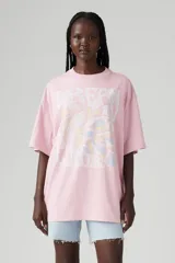 Remera rosa de corte holgado con estampado de texto e imagen abstracta en el frente.