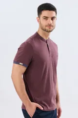 Remera estilo polo con cuello mao y manga corta, de color bordó con detalles en azul en los bordes de las mangas y cuello. Cuenta con cierre frontal parcial de tres botones y pequeño logo bordado en el pecho.