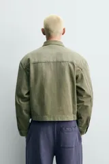 Cazadora cropped de algodón con efecto lavado, color verde militar. Presenta cuello solapa, cierre frontal con cremallera, bolsillos frontales de plastrón con solapa y parches decorativos en el pecho.