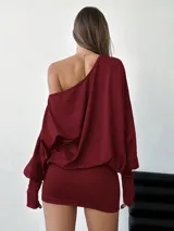 Vestido corto elastizado color bordó, asimétrico, con manga larga y hombro al descubierto.