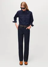 Camisa de denim de algodón azul oscuro, con cuello camisero, manga larga con puños abotonados, dos bolsillos frontales con solapa y cierre delantero de botones ocultos.