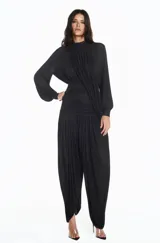 Pantalón de pierna amplia en tejido de punto negro con cintura de pala drapeada. Diseño de caída fluida que estiliza la silueta y aporta movimiento elegante.